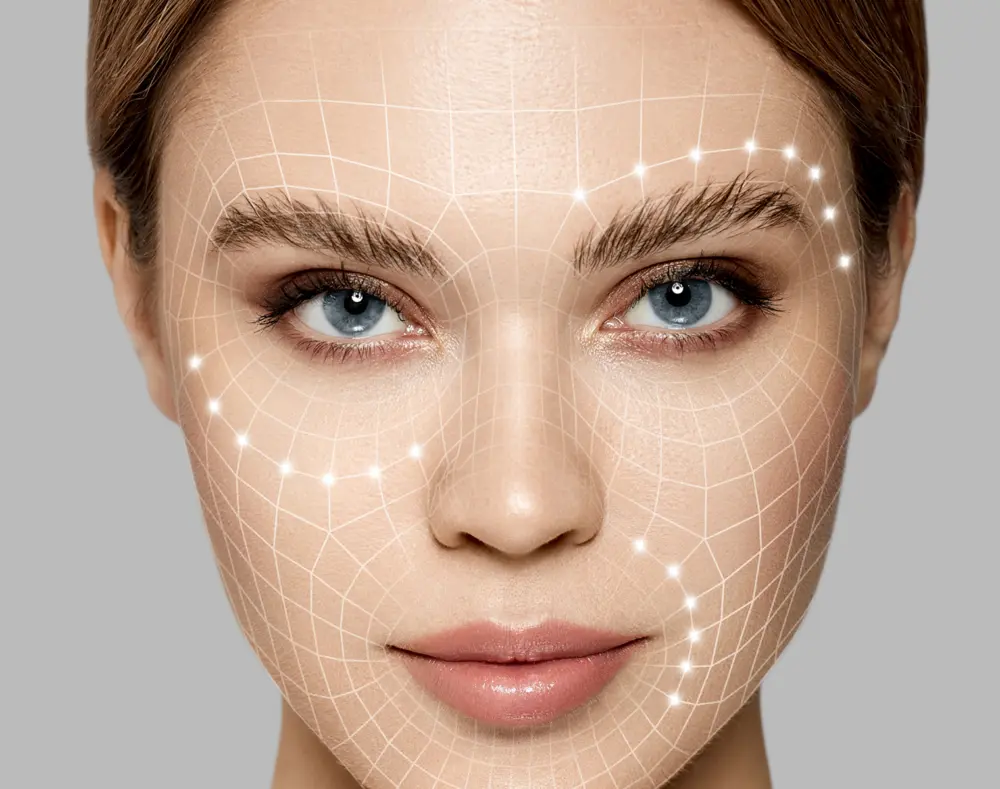 A close-up of a woman's face with blue eyes, with digital overlay of a facial recognition grid and glowing points highlighting key features.