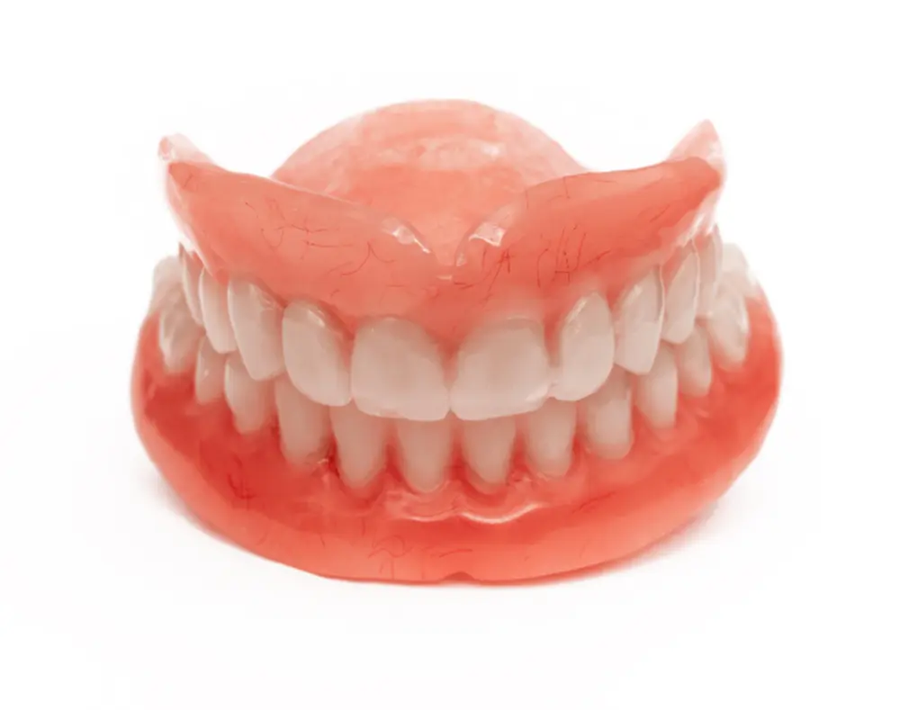 A set of realistic pink dentures with teeth attached, displayed against a plain white background.