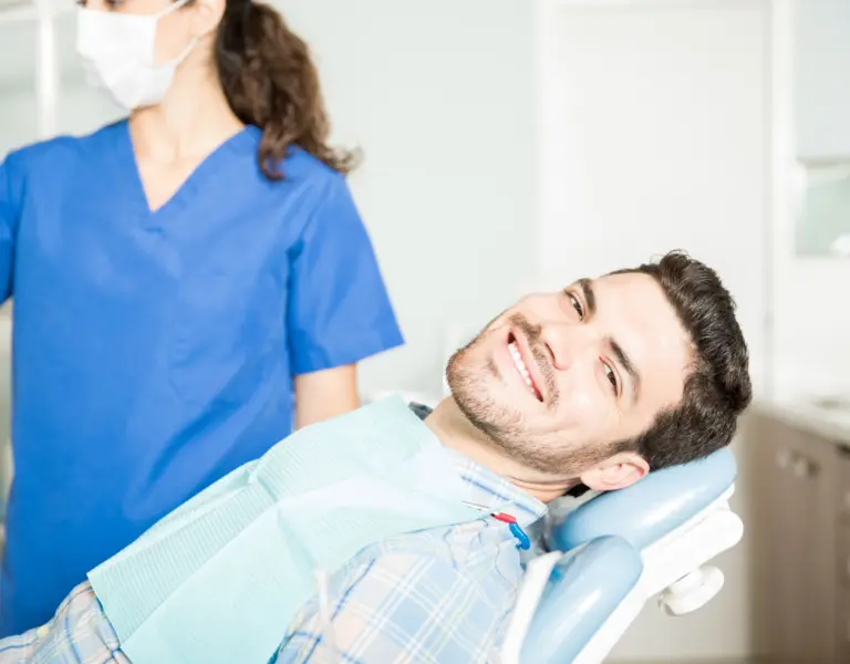 Portrait smiling mid adult man sitting chair by dentist clinic